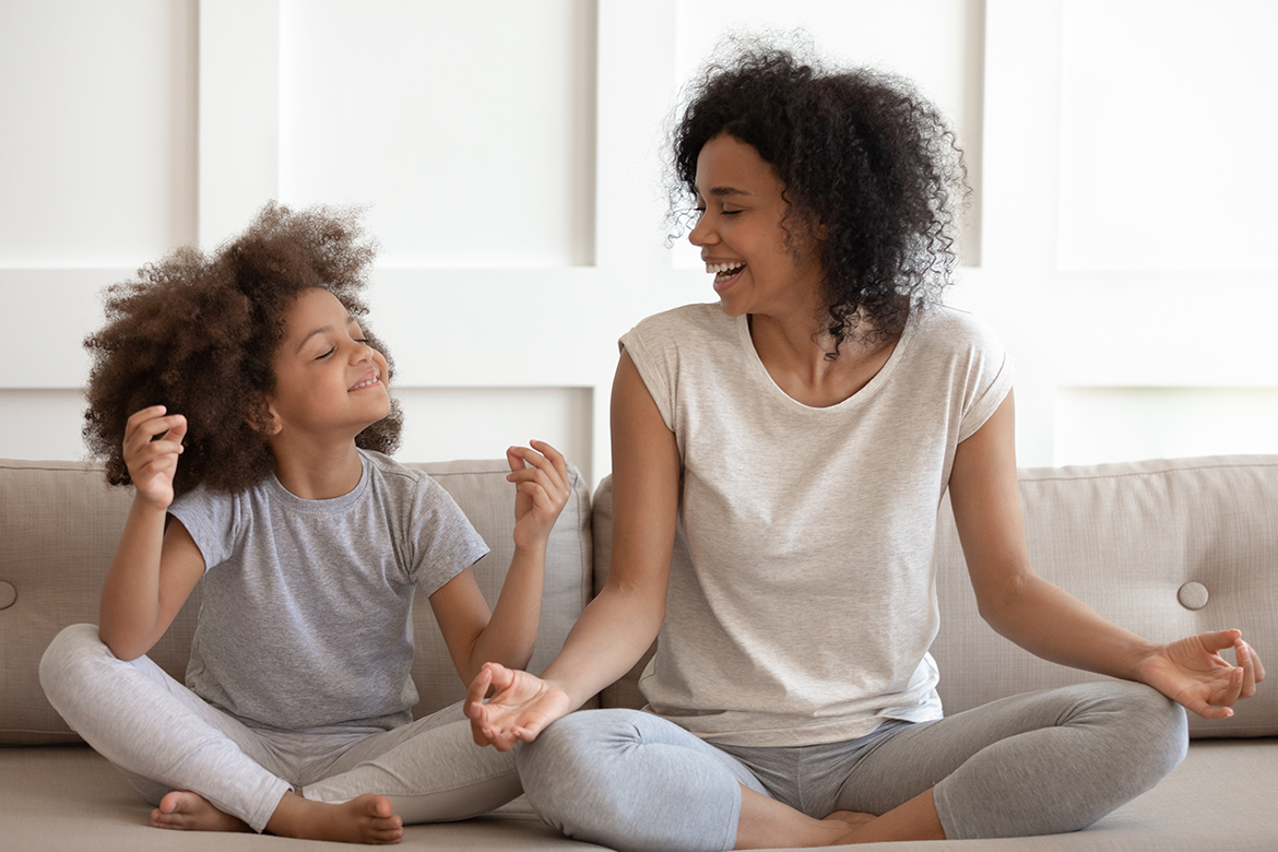 Mother and daughter enjoy relaxing yoga together in their quiet living room