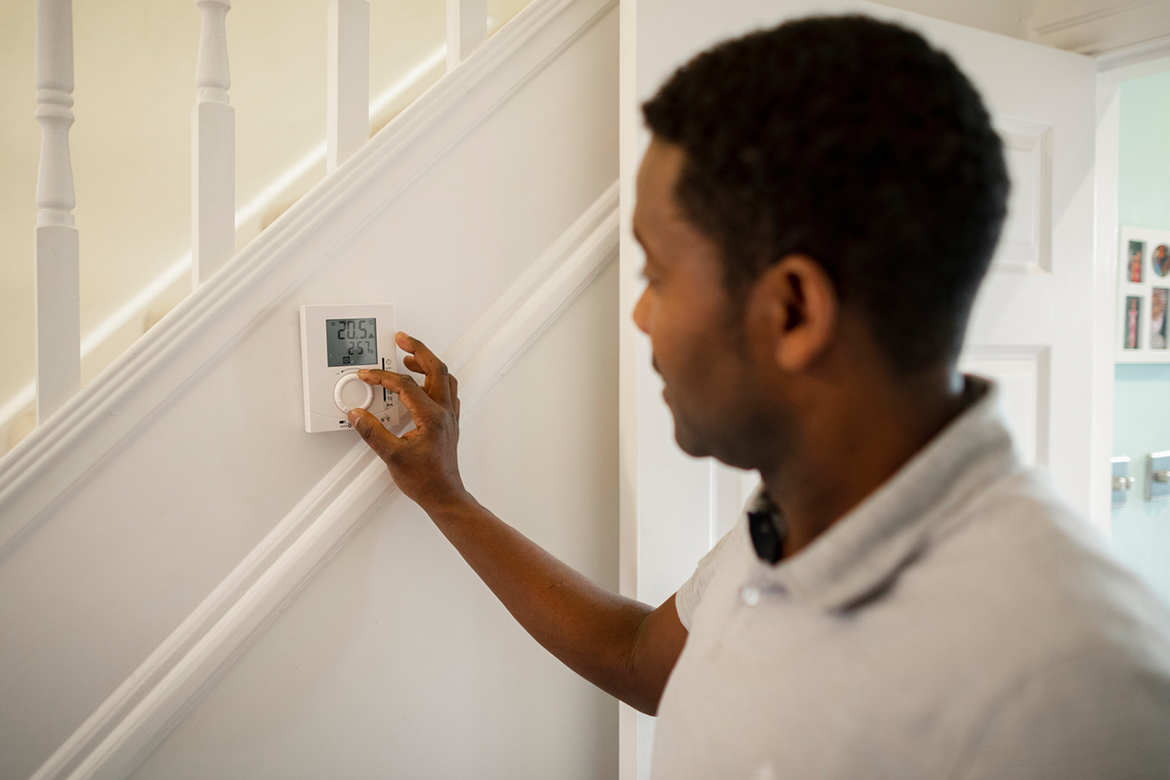 Man programs the thermostat in his home.