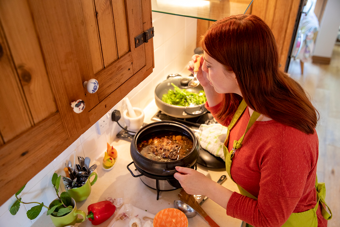 Woman tastes meal prepared in slow cooker to conserve energy